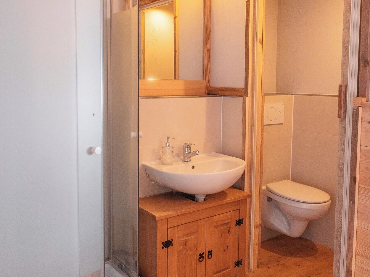 A bathroom with a wooden vanity, a white sink, and a toilet.