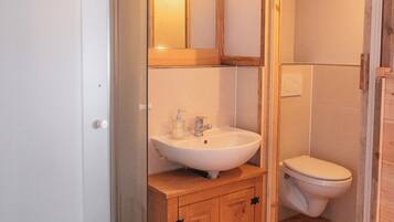 A bathroom with a wooden vanity, a white sink, and a toilet.