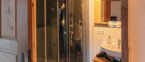 Un baño moderno con ducha de vidrio, un mueble de madera y un lavamanos con espejo.