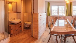 Une salle de bain au sol en bois, équipée d’un lavabo, de toilettes et d’une douche.