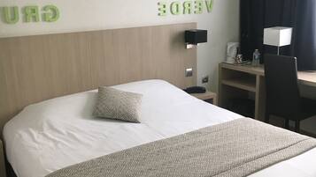 Habitación de hotel con una cama, un escritorio y una pared con letras verdes que deletrean "GREEN VERT".