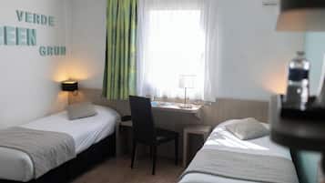 Una habitación con dos camas, un escritorio, una silla y un ventanal con cortinas.
