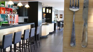 A modern kitchen with a bar area, bar stools, and hanging utensils. - Hôtel Relais d'Etretat (Bolbec)