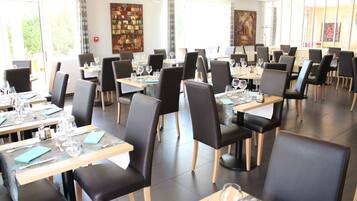 A restaurant with multiple tables and chairs, each set with wine glasses and cutlery.