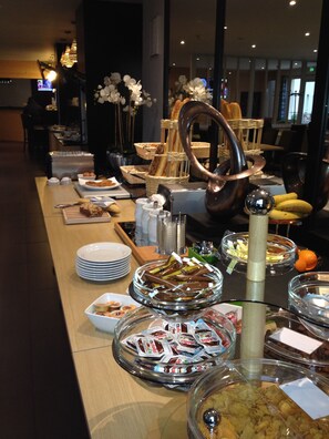 Montaje de bufé con diferentes alimentos y una escultura metálica decorativa.