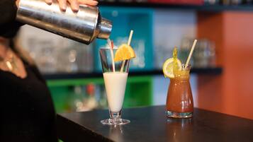 A bartender pouring a drink into a glass with a lemon slice and straw.