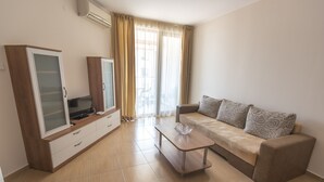 A modern living room with a sofa, a coffee table, a TV, and a cabinet. - Apollon Apartments (Nessebar)