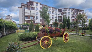 A residential building with multiple balconies, a playground, and a garden with a decorative cart. - Apollon Apartments (Nessebar)