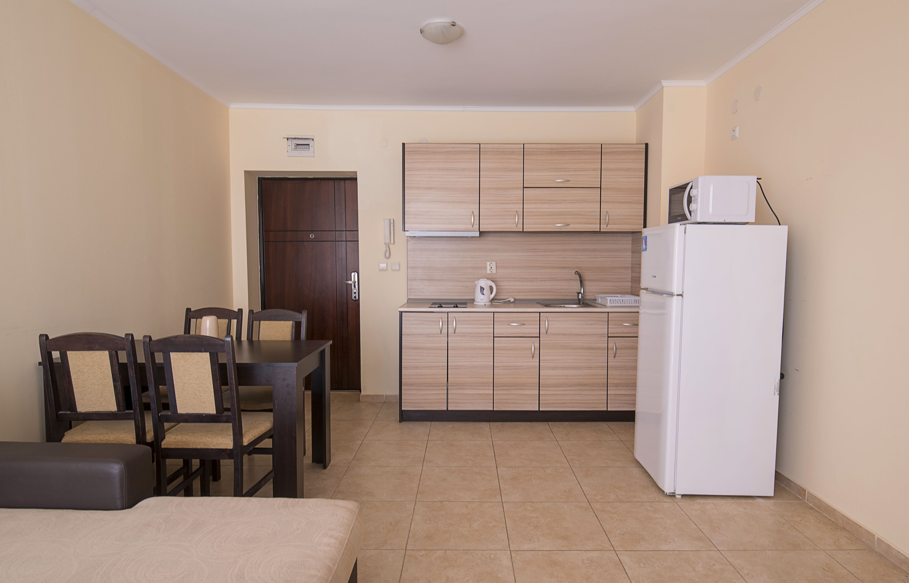 Una cocina compacta con armarios de madera, un refrigerador blanco y un comedor con mesa y sillas.