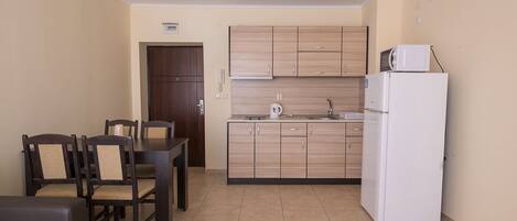 Una cocina compacta con armarios de madera, un refrigerador blanco y un comedor con mesa y sillas.