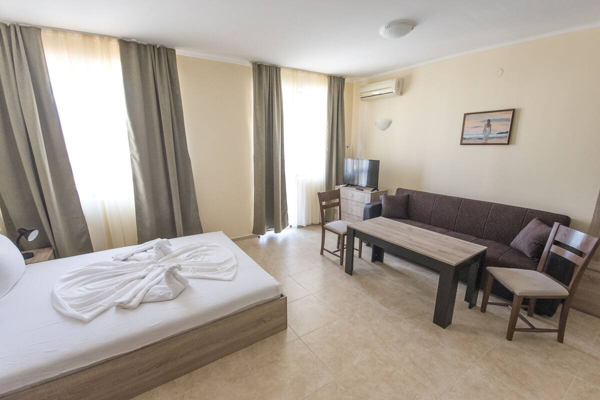 Quarto de hotel com uma cama, um sofá, uma mesa e uma televisão.