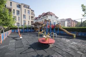 Children can play on the seesaw, slide, and climbing structure in this outdoor playground.