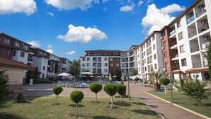 A courtyard with a swimming pool, lounge chairs, and umbrellas. - Apollon Apartments (Nessebar)