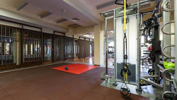 Un gimnasio con equipo de ejercicio, una colchoneta roja y un soporte para pesas.
