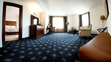 A hotel room with a bed, a desk, a chair, and a sofa.