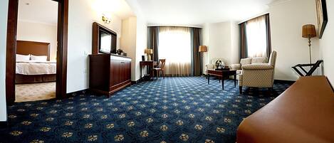 A hotel room with a bed, a desk, a chair, and a sofa.