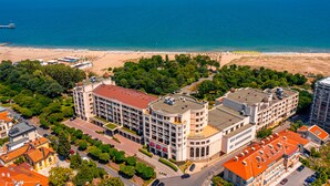 Um hotel à beira-mar com vários edifícios, uma praia e um cais.