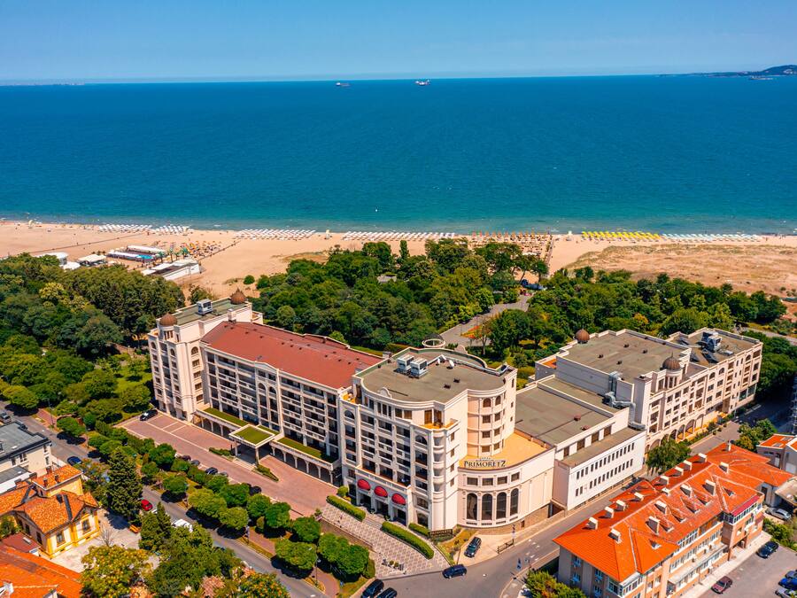 Um hotel à beira-mar com vários edifícios, uma praia e um cais.