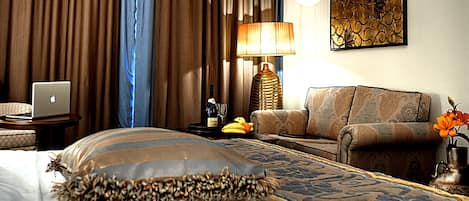 Una habitación de hotel con una cama, un ordenador portátil, una lámpara, un sofá y un adorno en la pared.