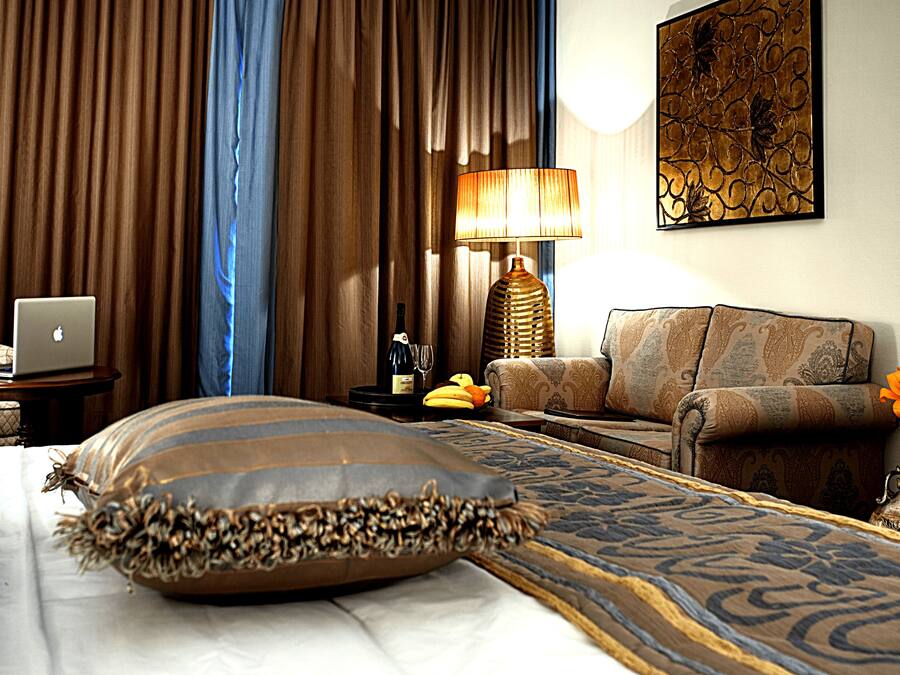 Una habitación de hotel con una cama, un ordenador portátil, una lámpara, un sofá y un adorno en la pared.