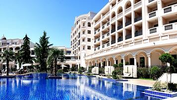 Un hotel con una piscina grande, varios balcones y jardines exuberantes.