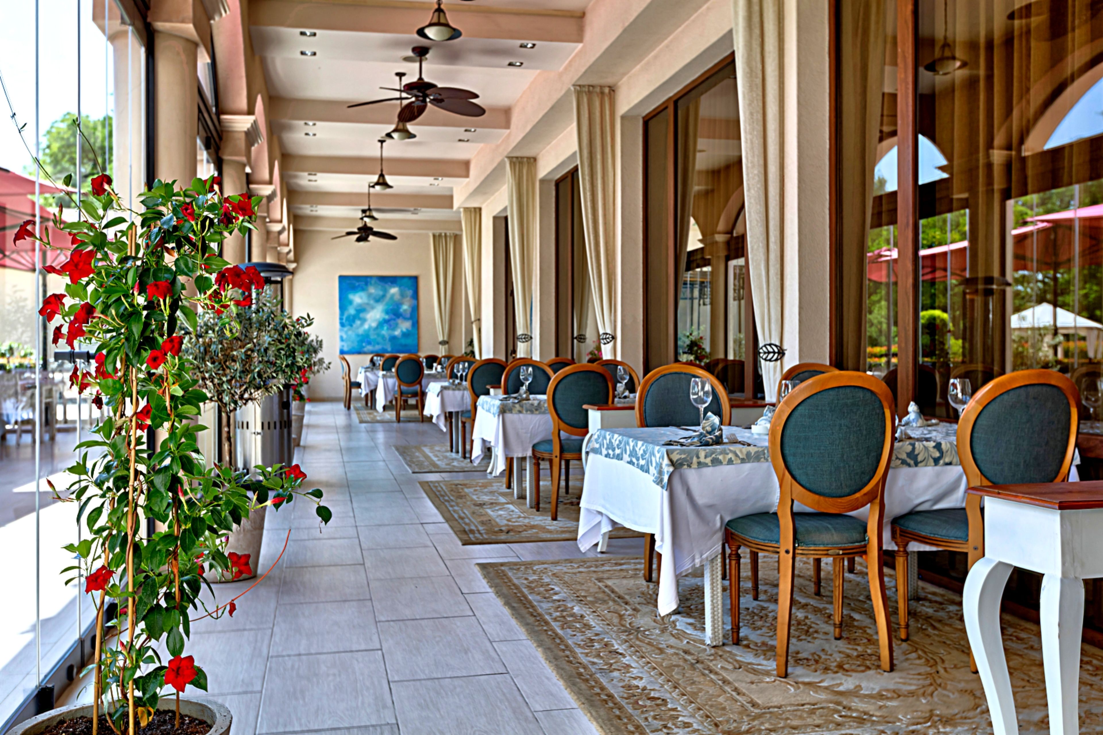 Un restaurante con terraza, plantas en macetas y ventiladores de techo.