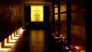 Um corredor com pouca luz, com uma placa indicando "the 6th Sense SPA" e velas ao longo do chão.
