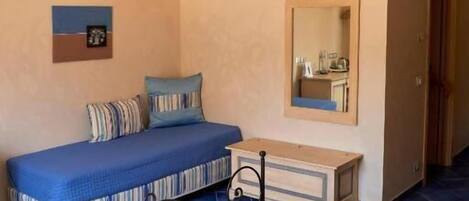 A bedroom with a bed, bedside table, and a mirror.