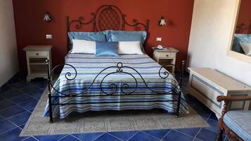 Un letto con struttura in metallo, una coperta a righe blu e bianche e due comodini con lampade.