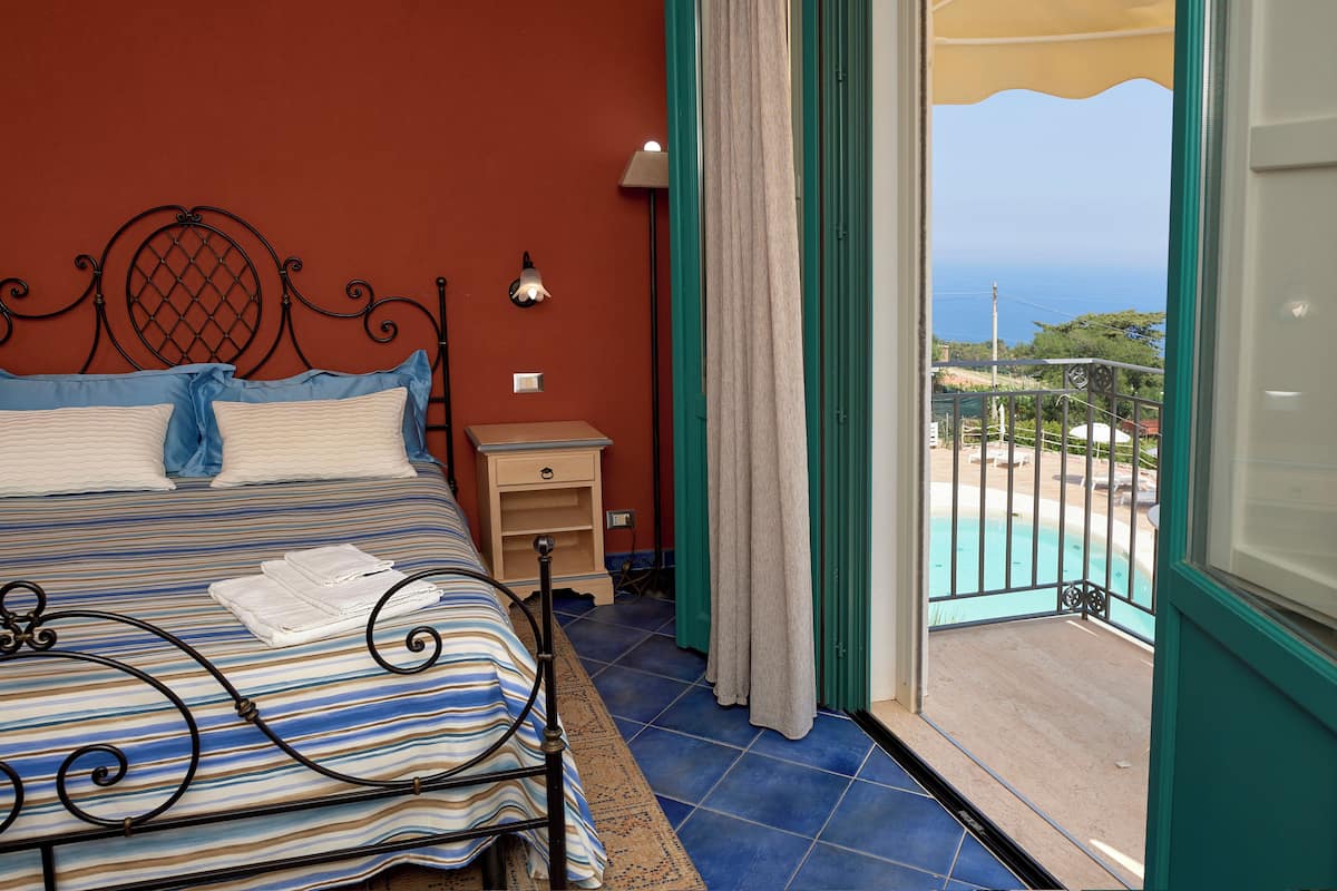 Un dormitorio con cama, mesita de noche y vistas a una piscina y al océano.