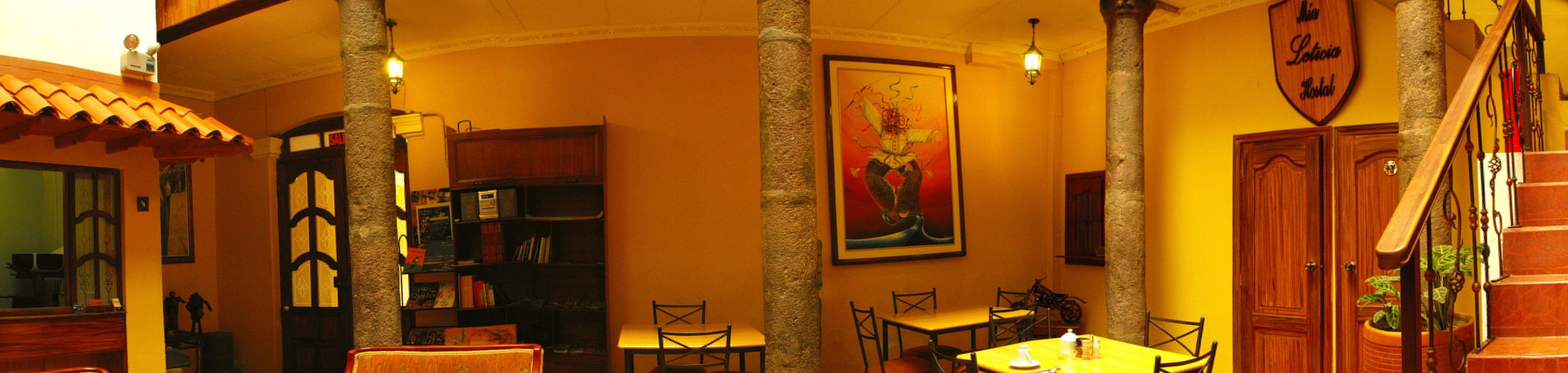 A cozy interior with a staircase, wooden bookshelves, a dining area, and a mural.