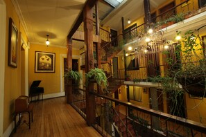 A multi-level interior with wooden floors, a piano, and a chandelier. - Mia Leticia B&B. (Quito)