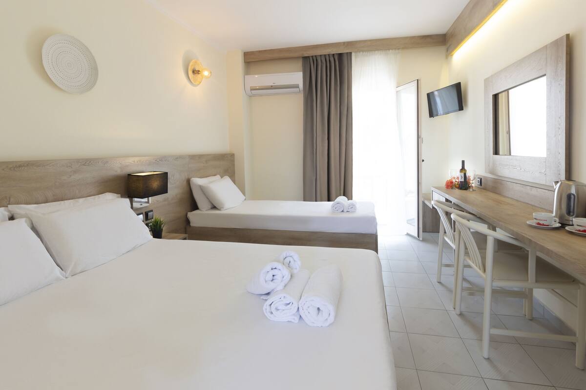 A hotel room with two beds, a desk, a TV, and a mirror.