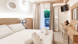 A hotel room with a large bed, a desk with a coffee maker, and a TV mounted on the wall. - Hotel Odysseas (Kassandra)