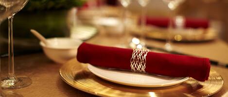 A table set with a gold-rimmed plate, a red napkin, and a clear glass.