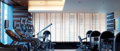 A modern gym with treadmills, elliptical machines, and weight equipment.