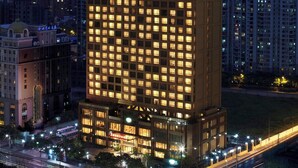 Un hotel moderno de gran altura con una fachada de ventanas en forma de cuadrícula, el logotipo de Marriott y un patio interior.