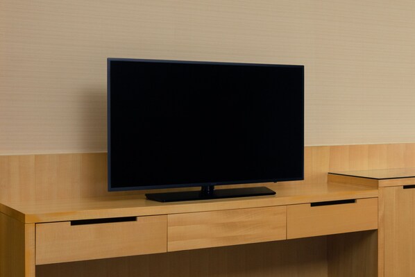 Un televisor de pantalla plana sobre un escritorio de madera con cajones.