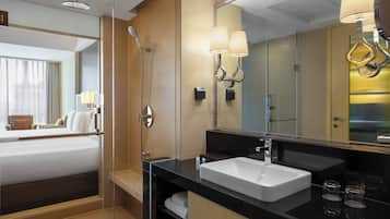 A hotel bathroom with a large mirror, a sink, and a shower.
