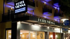 A hotel named "HOTEL VIENNA" with a signboard, entrance, and outdoor seating area. - Hotel Vienna (Jesolo)