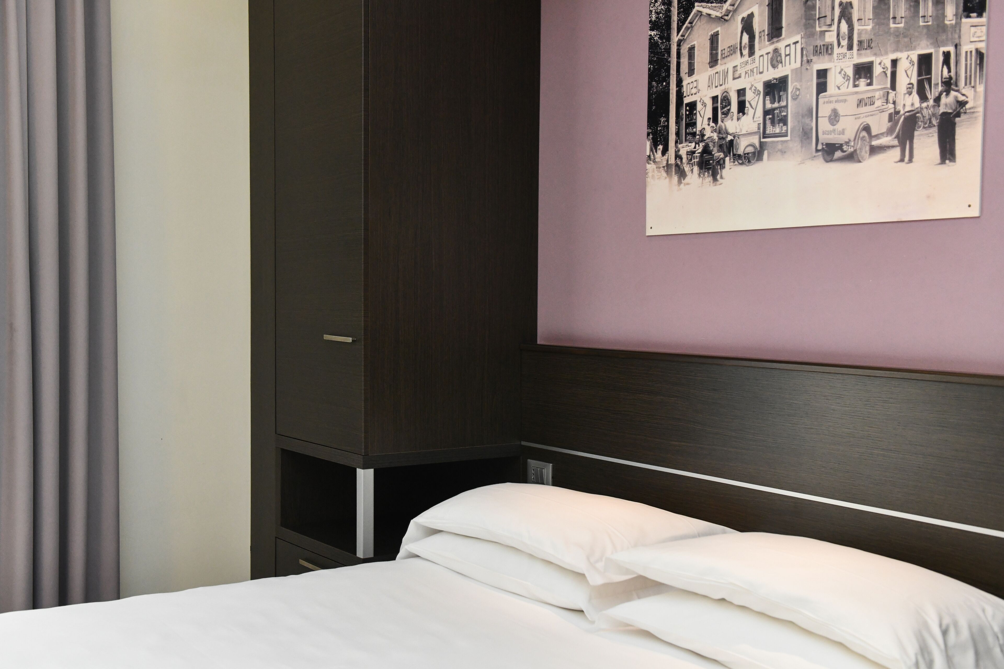 Une chambre d’hôtel avec un lit, une armoire et un tableau accroché au mur.