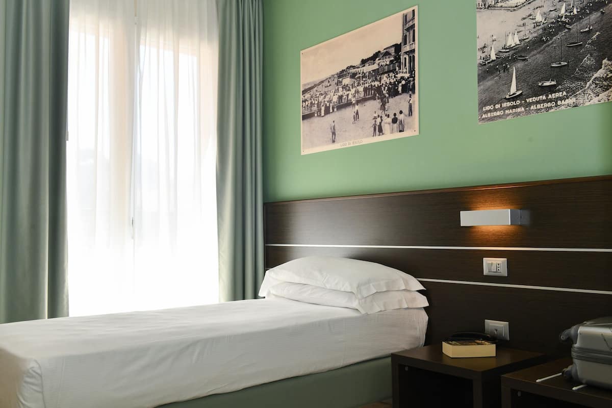A hotel room with a bed, a nightstand, and a wall-mounted lamp.