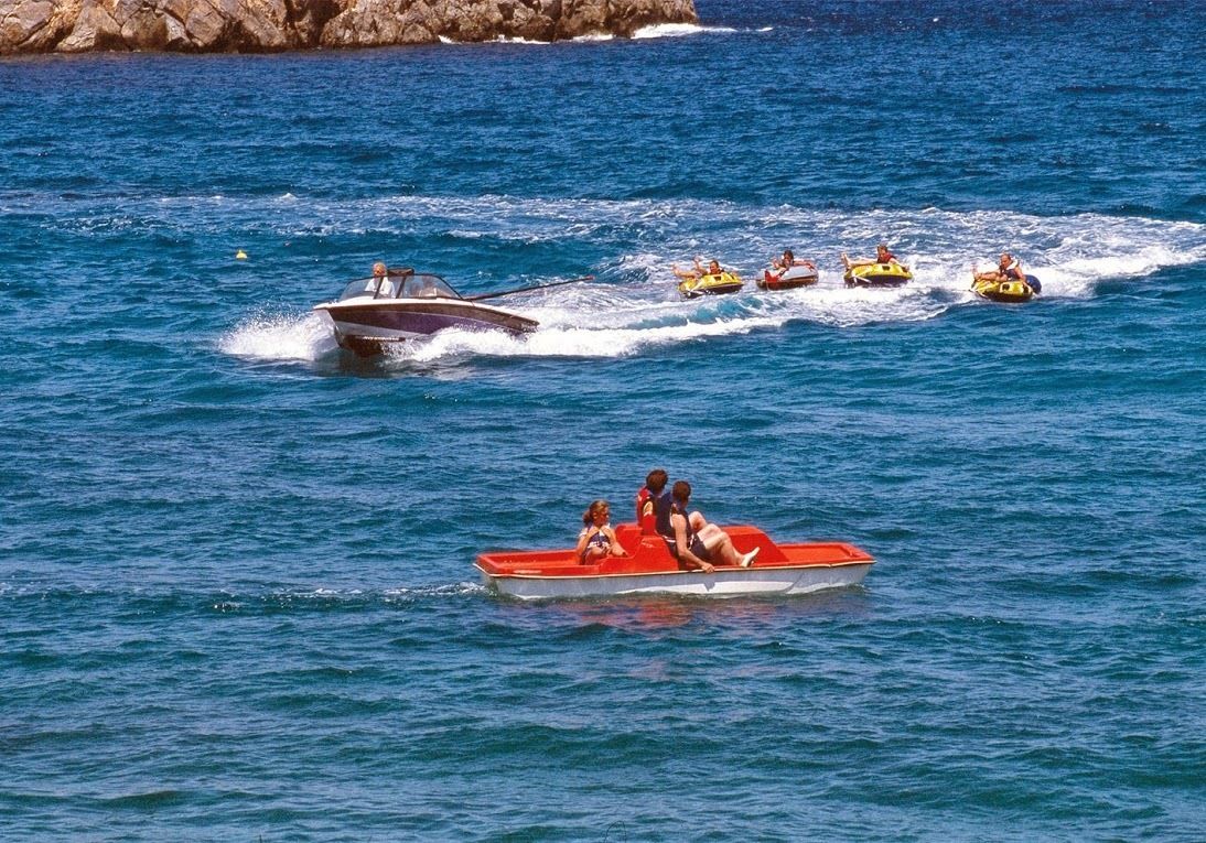 A boat with passengers and several inflatable rafts in the water.