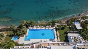 Una piscina al aire libre, sombrillas, sillones reclinables de piscina