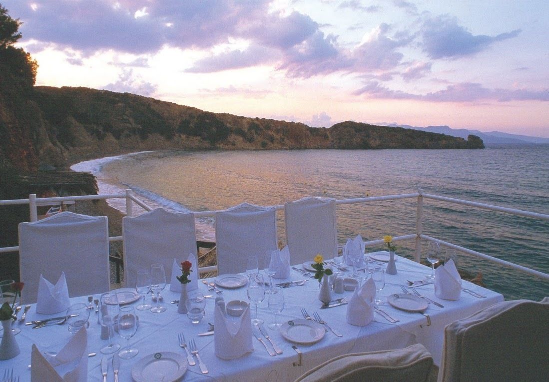 Una mesa lista para una comida con vistas al mar y a los acantilados.