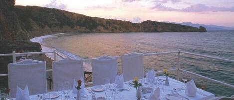 Una mesa lista para una comida con vistas al mar y a los acantilados.