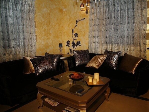 A living room with a dark brown sofa, a glass-top coffee table, and a decorative plant.