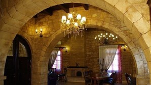 A stone-walled room with a chandelier, a dining table, and chairs. - Palazzo Loupassi Villas (Platanias)