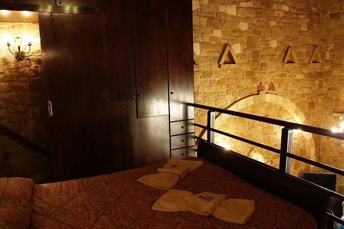 Une chambre d’hôtel avec un mur en pierre, une armoire en bois et un lit avec des serviettes.