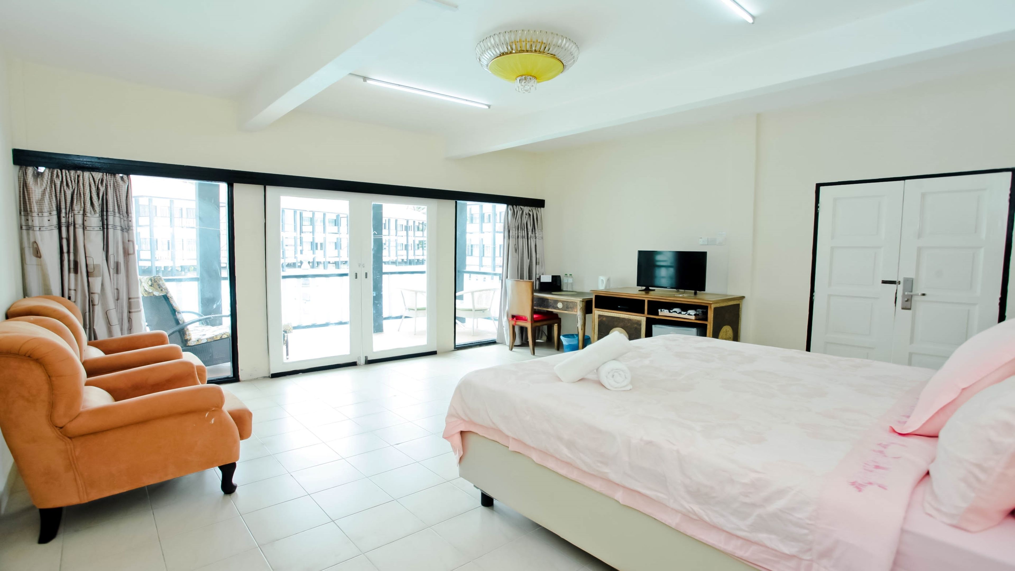 A hotel room with a bed, a desk with a TV, a chair, and a sofa.